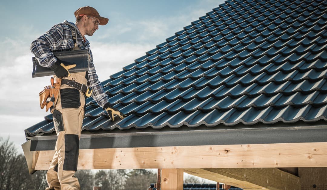 Roofer fitting new roof tiles on a house roof